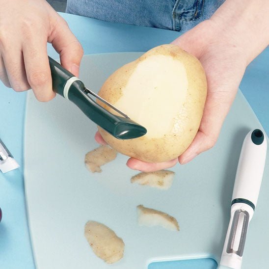 économe épluchage de pomme de terre au dessus d'une planche